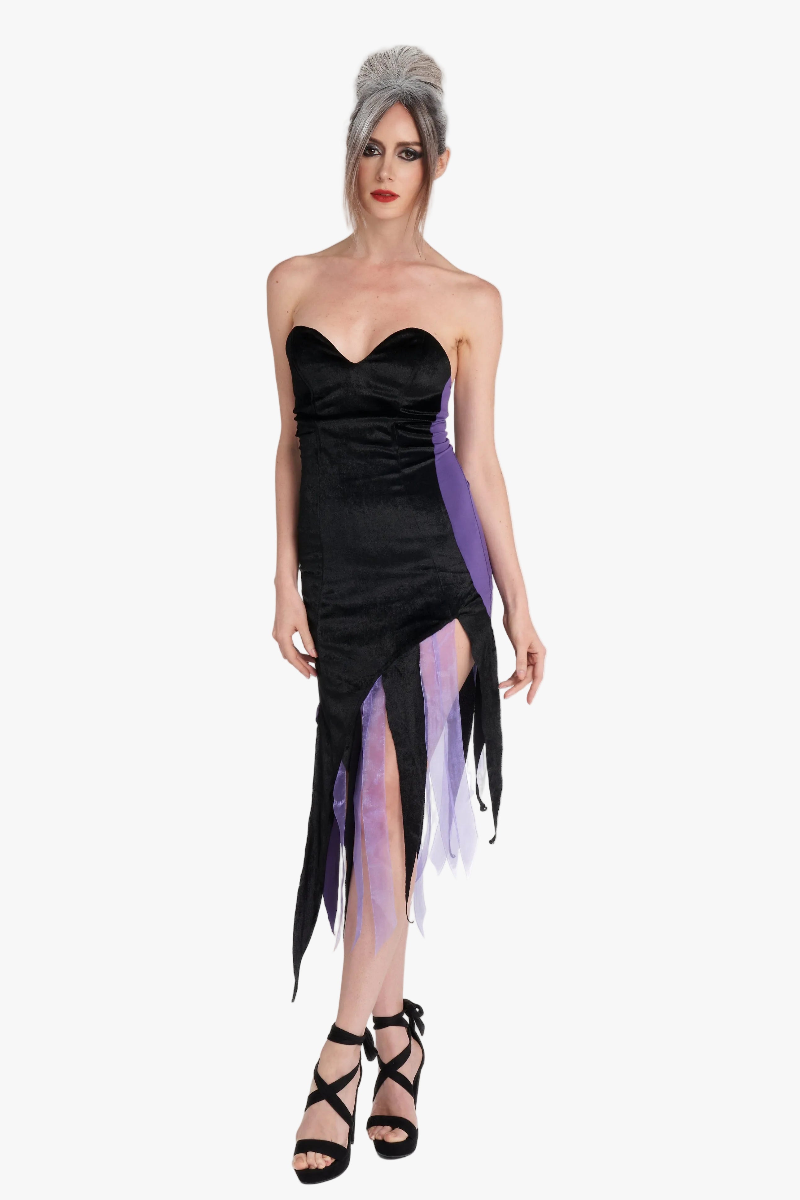 A woman modeling aa Ursula costume strapless black dress with purple tulle accents and long dangling black fabric at the hem, photographed against a plain light gray studio background.