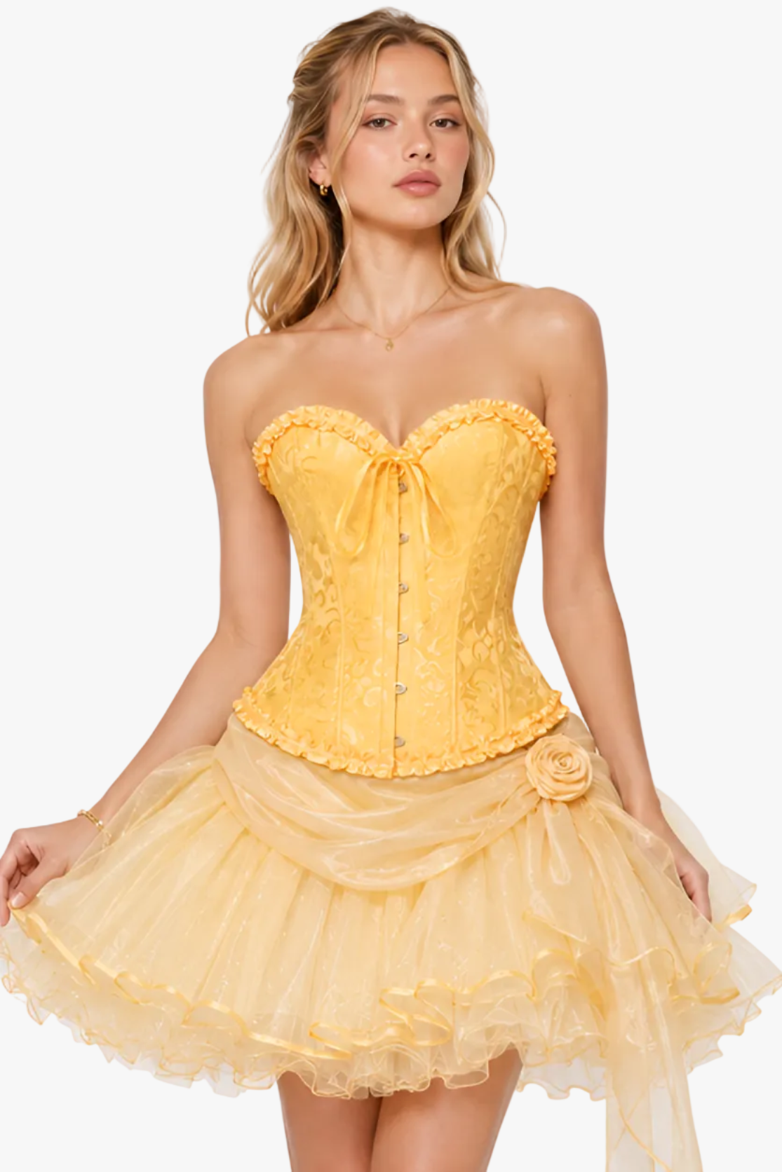 A woman modeling a strapless yellow dress with a lace corset-style bodice, ruffled trim, and a layered tulle skirt against a plain light gray studio background.