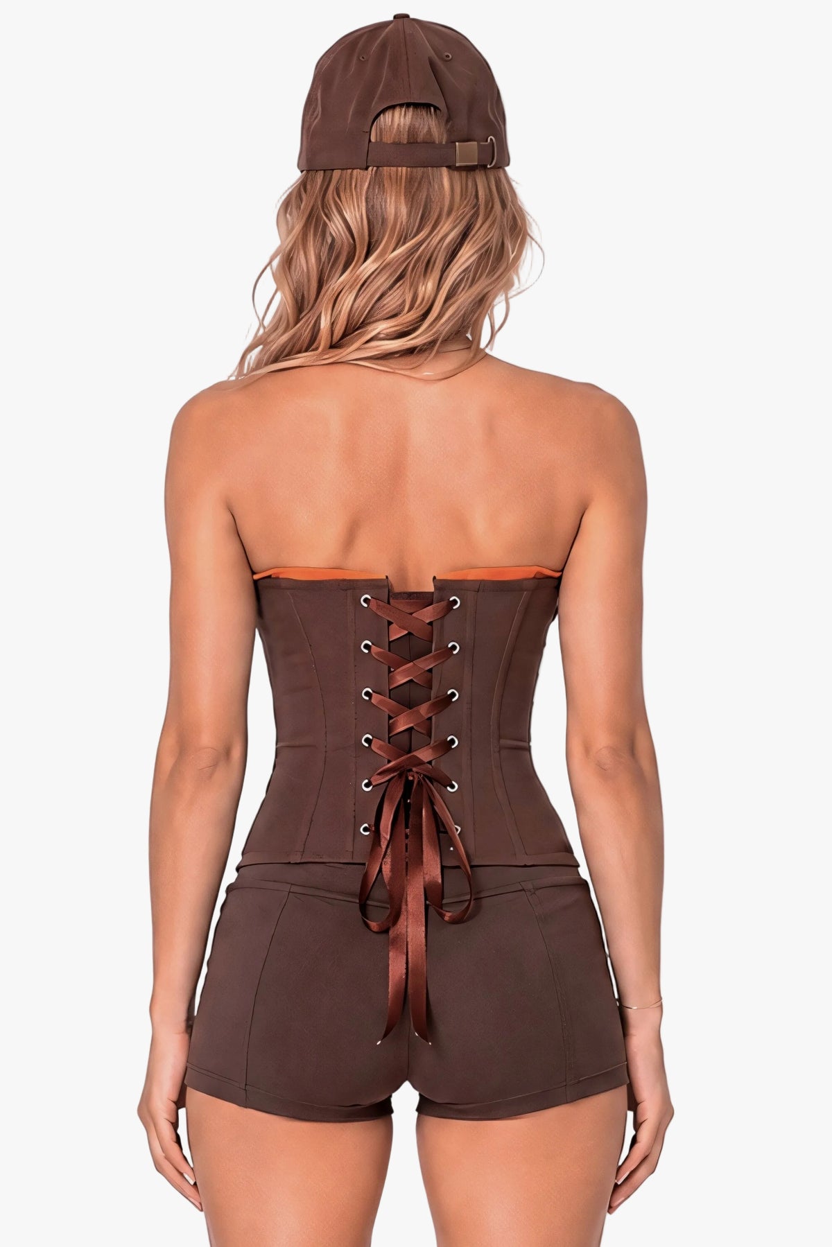 A woman shown from the back wearing a brown strapless corset-style top with lace-up back detail and matching brown shorts, along with a brown baseball cap, against a plain light background.