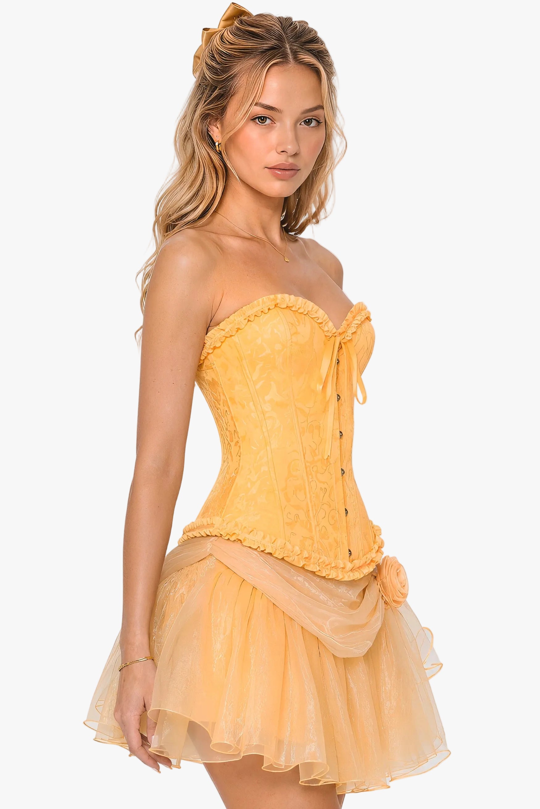A woman modeling a belle princess yellow strapless corset with a lace corset top, sheer tulle skirt, and matching fabric bow detail, photographed against a plain light gray studio background.