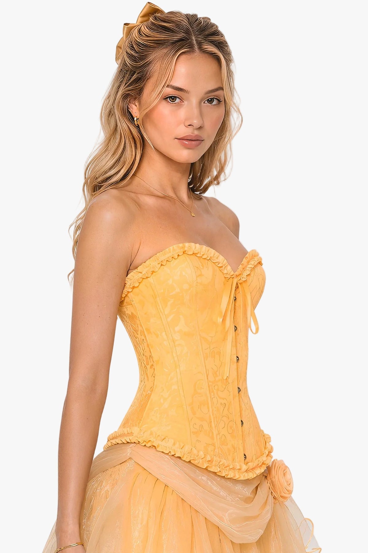 A woman modeling a belle princess yellow strapless corset with a lace corset top, sheer tulle skirt, and matching fabric bow detail, photographed against a plain light gray studio background.