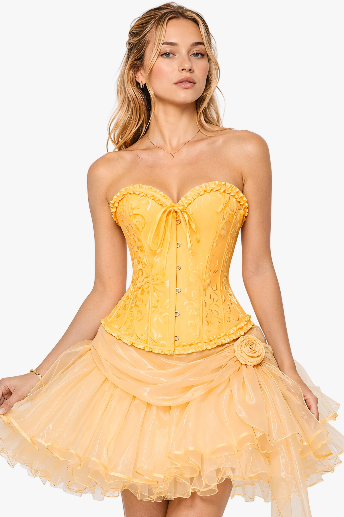 A woman modeling a strapless yellow corset with a sweetheart neckline, lace-up front, embroidered bodice, and layered tulle skirt against a light gray studio background.