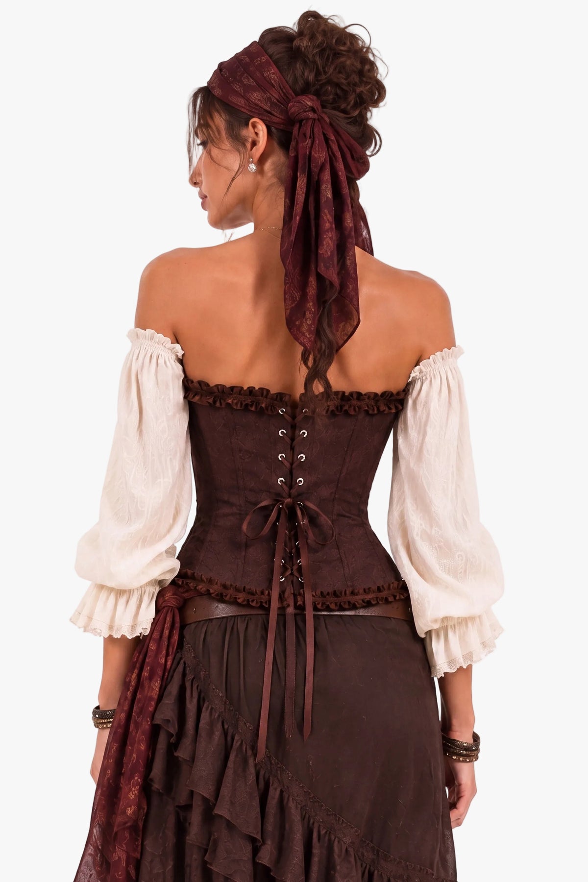 A woman shown from the back wearing a historical-style off-the-shoulder dress with a dark brown corset, cream puff sleeves, and a dark brown ruffled skirt, against a plain white background.