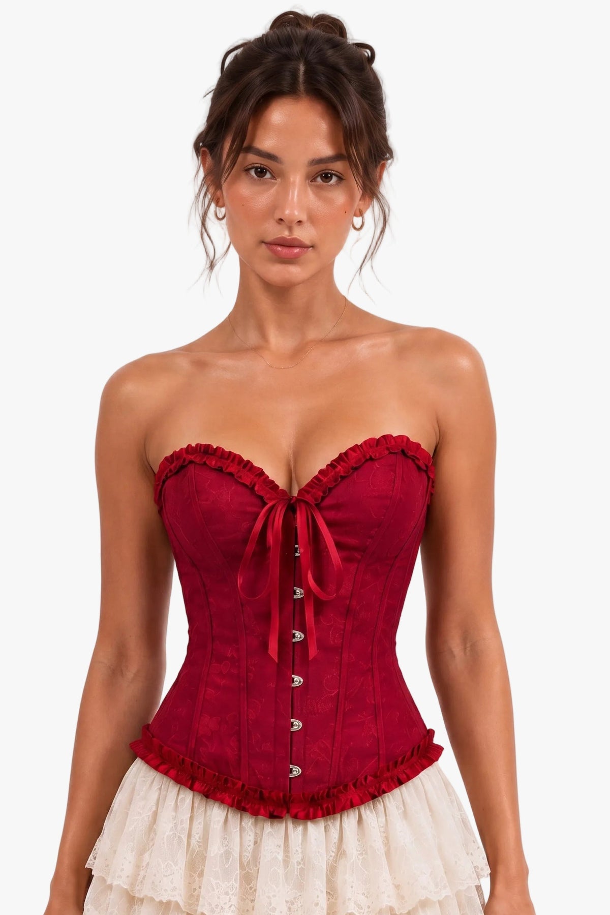 A woman modeling a strapless corset top in deep red with a matching red bow and lace trim, paired with a cream ruffled skirt, against a plain white studio background.