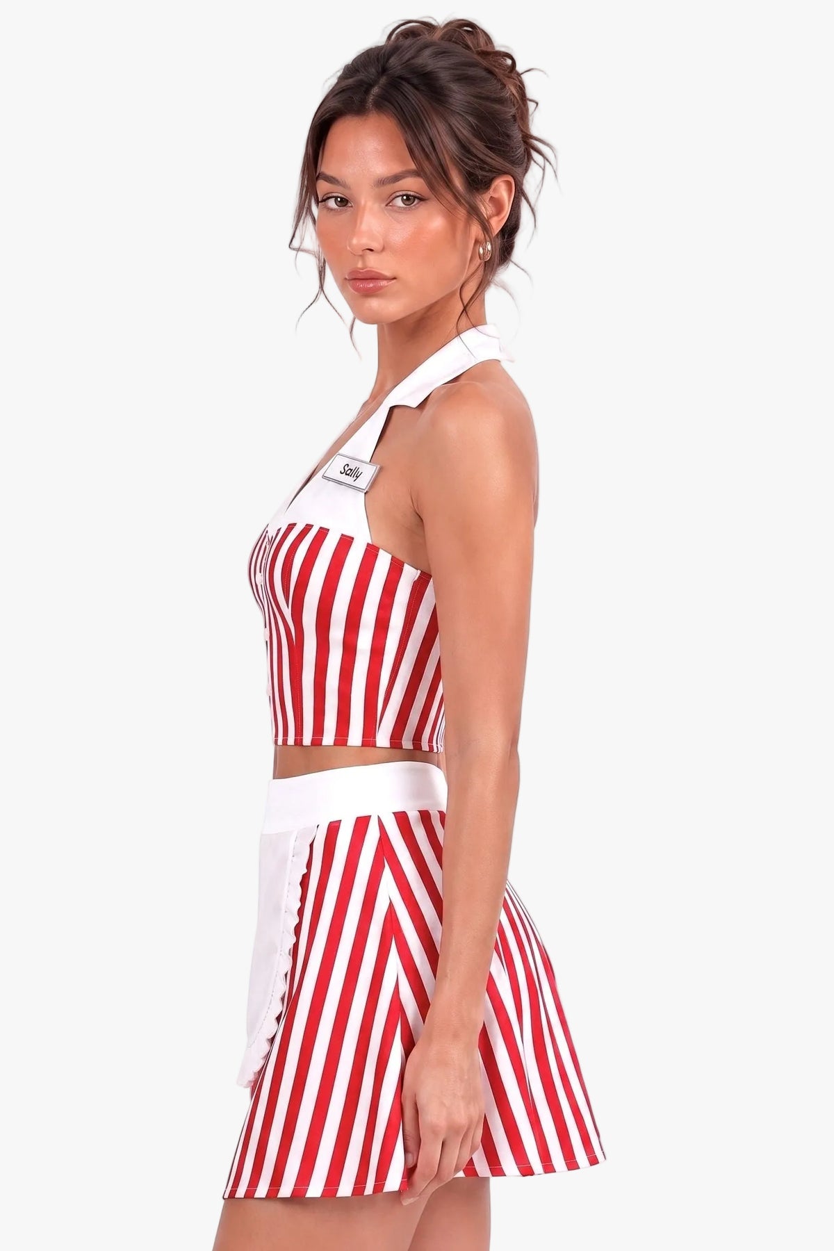 A woman modeling a red and white vertically striped two-piece outfit consisting of a halter crop top and a matching mini skirt, set against a plain white studio background.