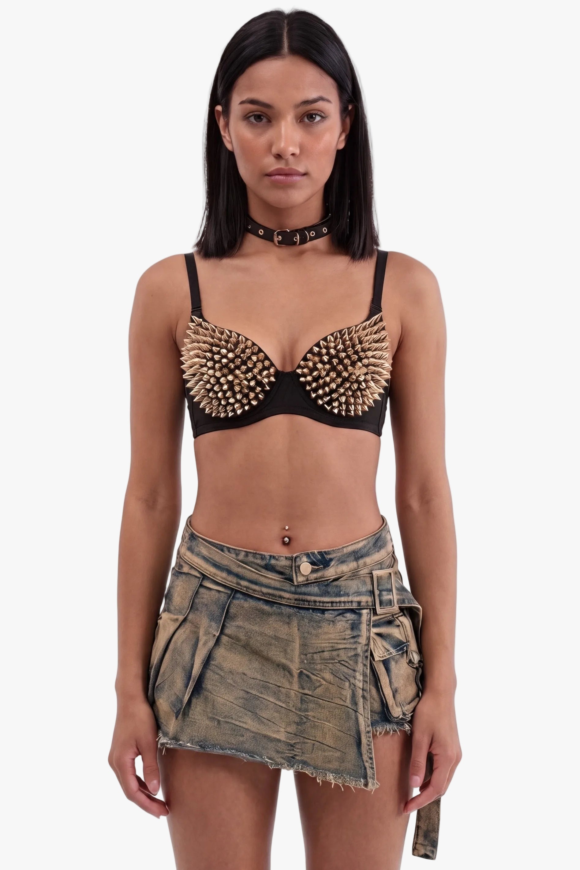 A model wearing a black studded bralette with denim cargo shorts, a black choker, and a belly button ring, shot against a solid white background.