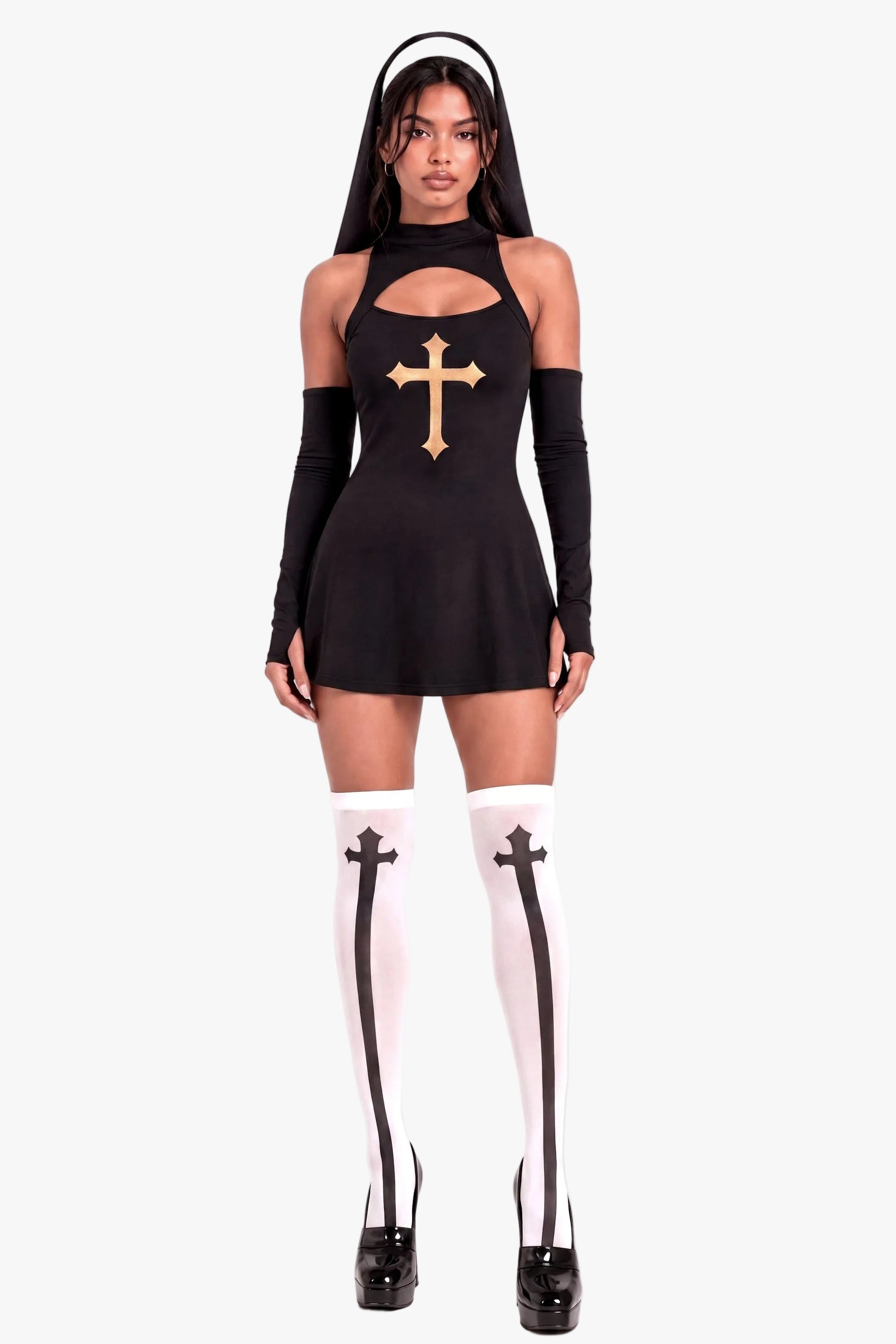 A model wearing a black gothic nun costume dress with a gold cross on the chest, long black arm warmers, white thigh-high stockings with black straps, and black platform heels, set against a plain white studio background