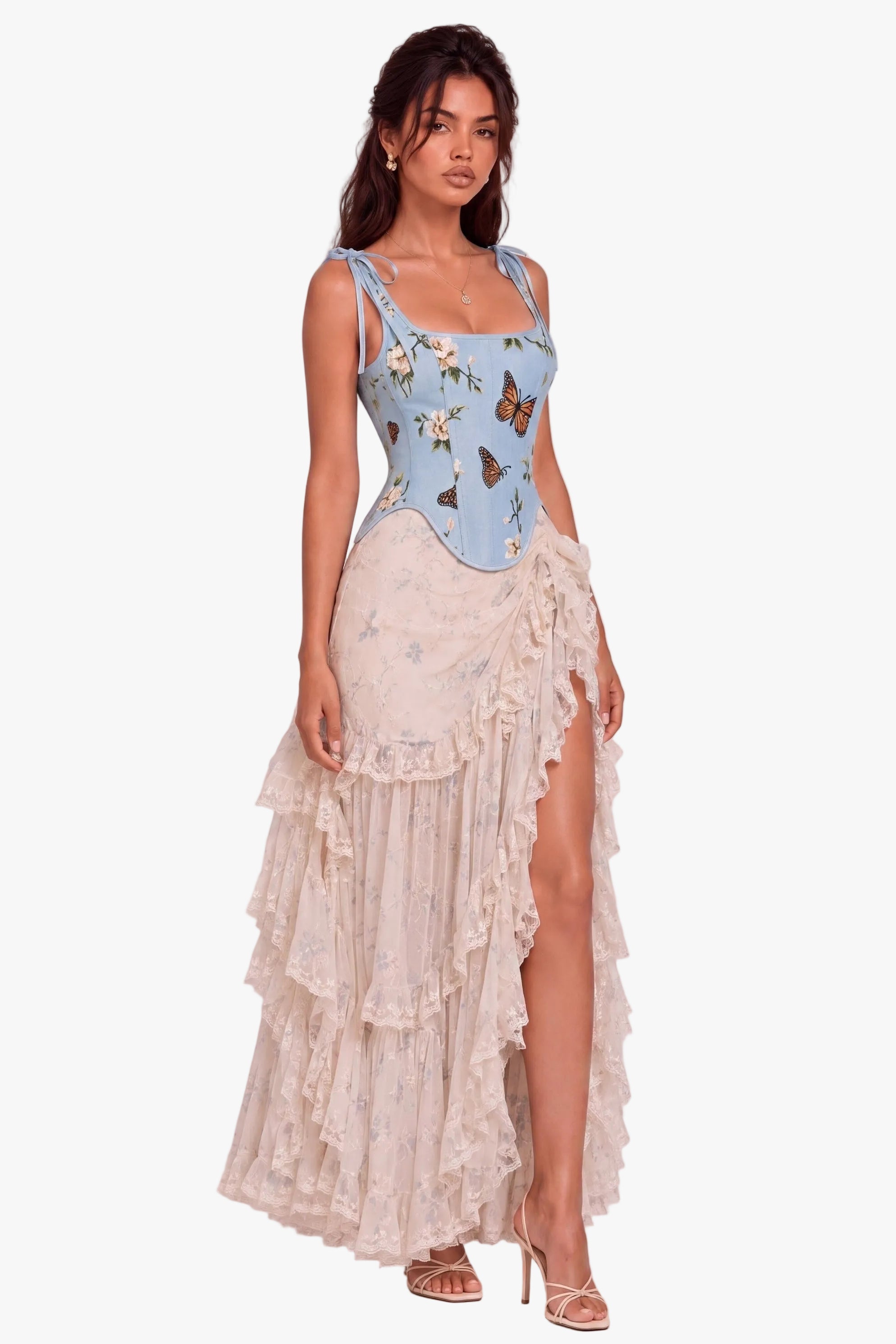A model wearing a light blue sleeveless top with a butterfly print and a long, tiered cream ruffled skirt, standing against a neutral light gray studio background.