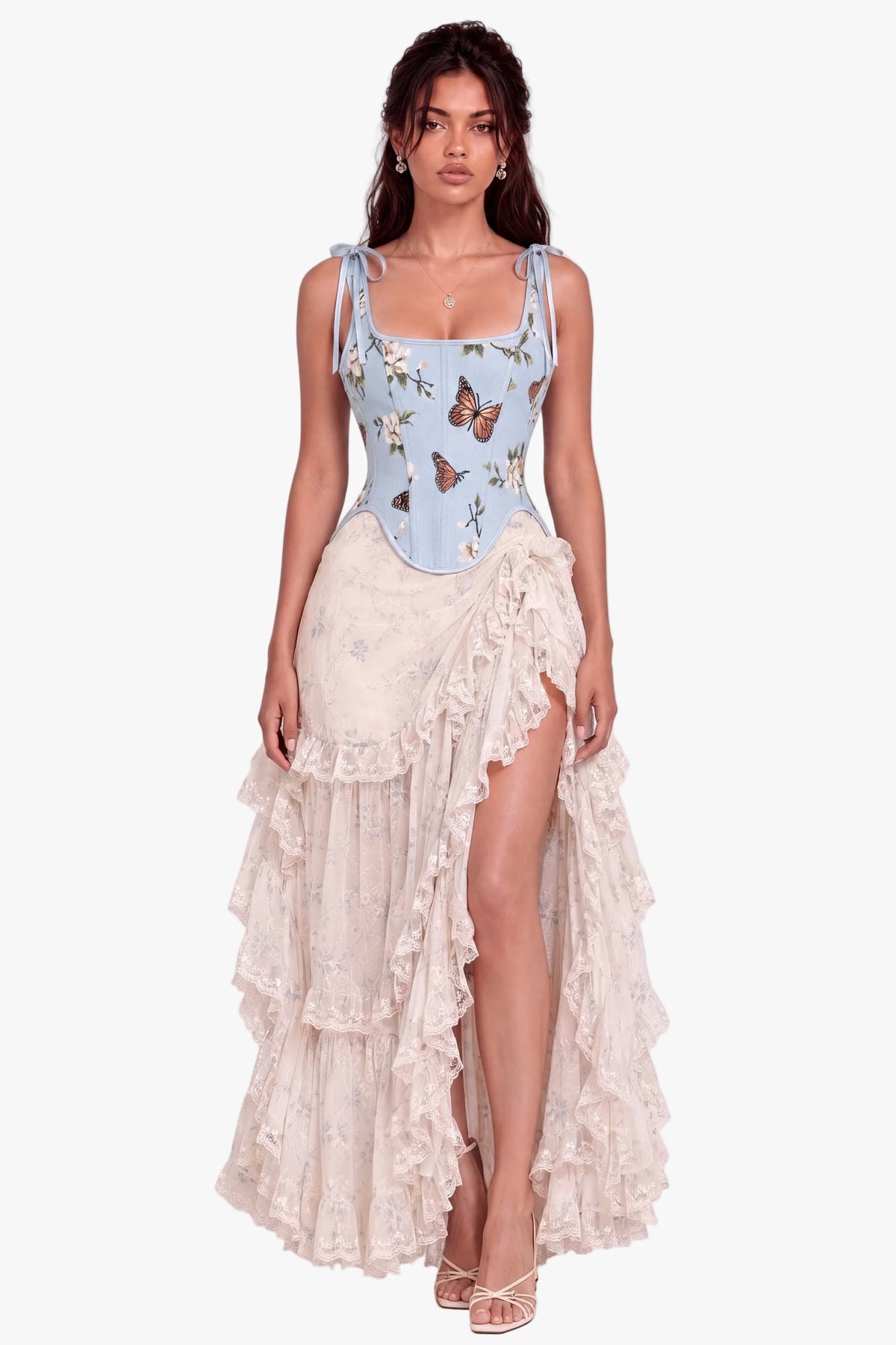 A model wearing a light blue sleeveless corset top with a butterfly print and a long cream ruffled asymmetrical skirt, standing against a plain light beige studio background.