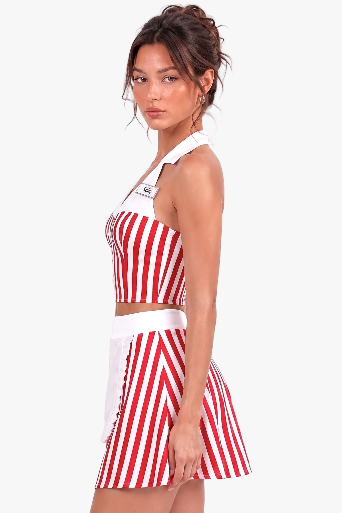 A woman modeling a red and white vertically striped two-piece diner girl outfit consisting of a halter crop top and a matching mini skirt, set against a plain white studio background.