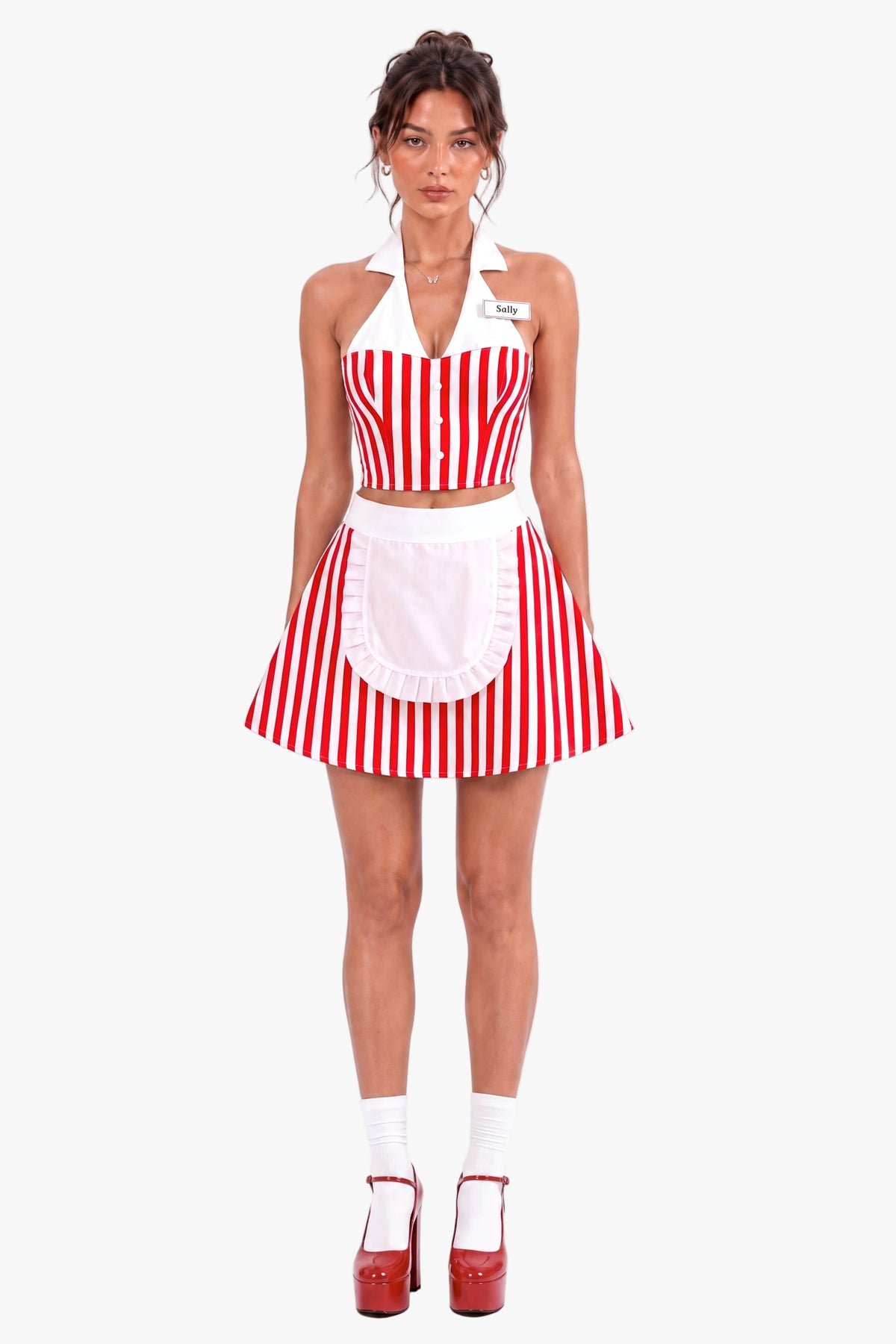 A woman modeling a red and white vertically striped diner costume set consisting of a halter crop top, matching skirt, and a white apron with a ruffled hem. She is wearing a name tag that says 'Sally' against a plain white background.