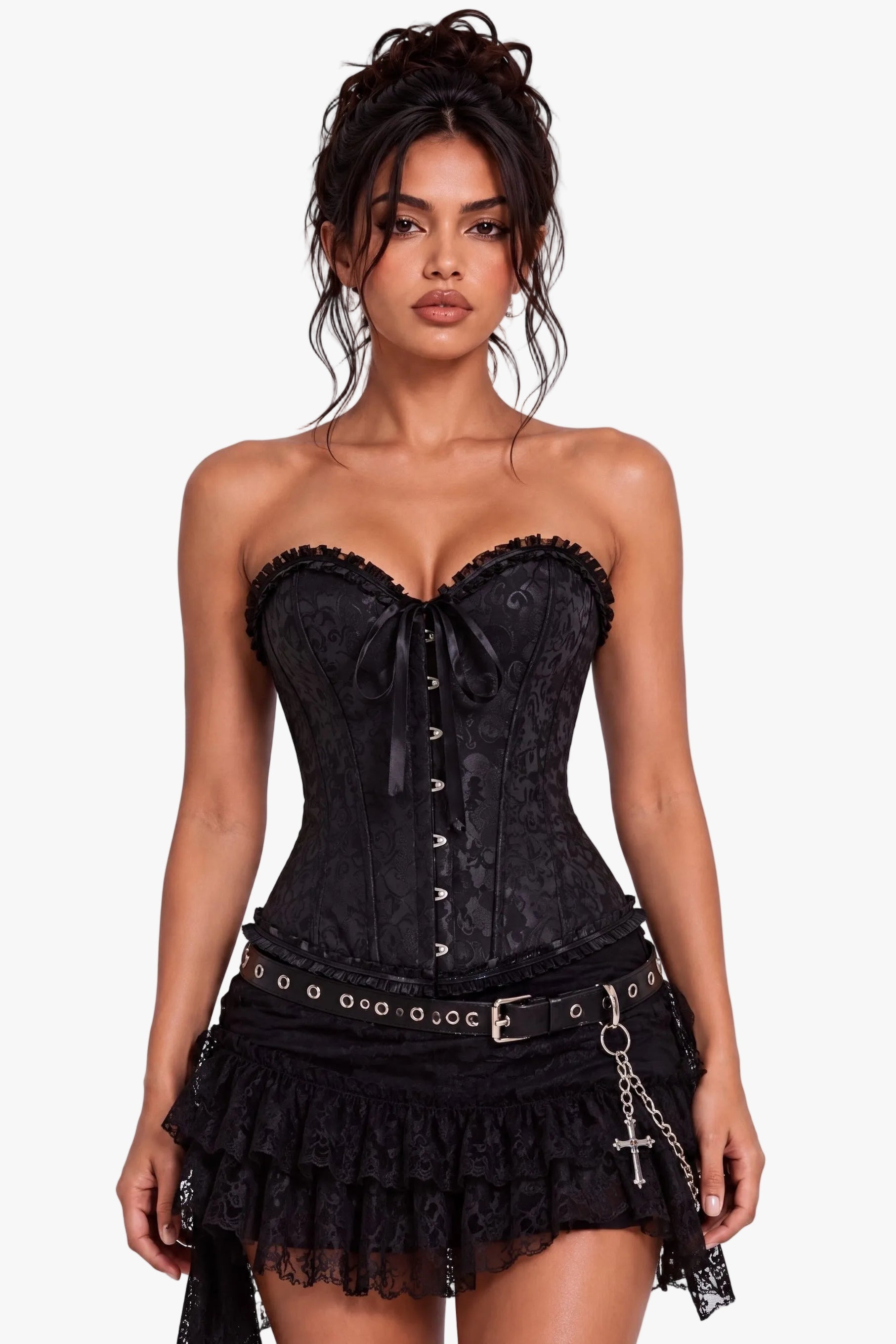 A model wearing a black lace and satin corset mini dress with a ruffled skirt, studded belt, and cross chain accessory, set against a plain light gray studio background.