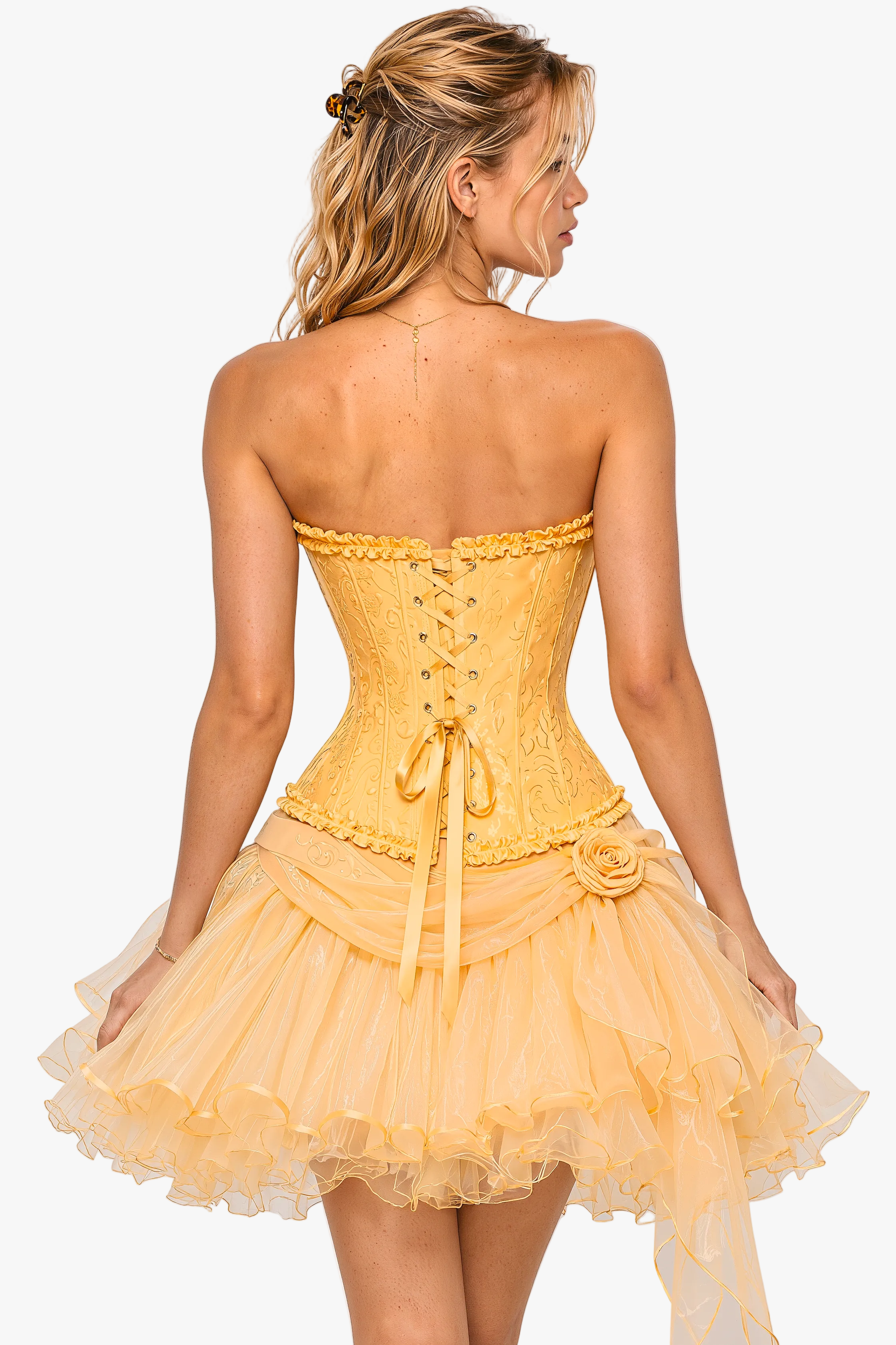 A woman shown from the back wearing a yellow strapless corset-style mini dress with a ruffled tulle skirt, photographed against a light gray studio background.